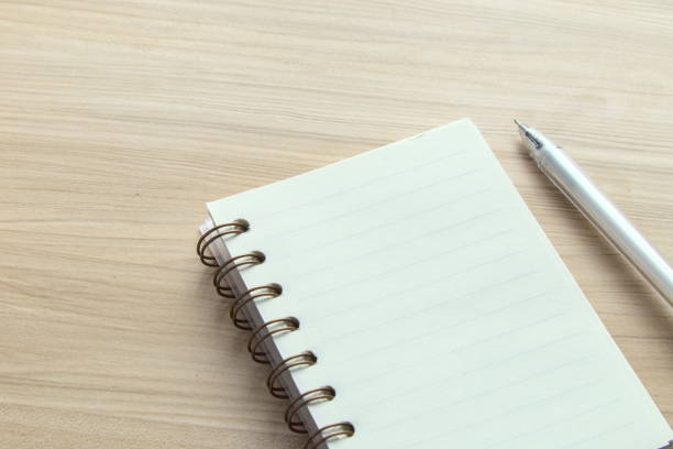 istock Open spiral-bound notebook and pen pn desk, blank for your text, workplace 1294242167