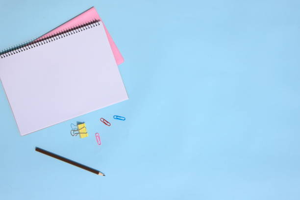 istock Open notebook, pencil, paper clips. Office supplies on blue background, blank with copy space 1294242528