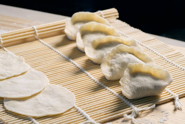 Raw dumplings and dumpling skins on bamboo mat, homemade dumplings