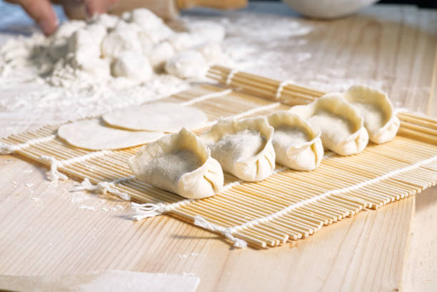 Dumplings and dumpling skins on bamboo mat, blur background, Chinese food