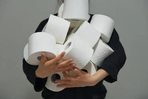 Asian woman carrying multiple rolls of toilet paper, paper crisis concept, storing toilet paper