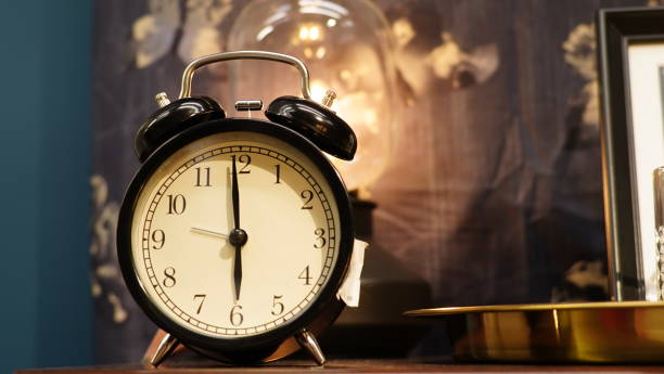 istock Black vintage alarm clock on the table, showing 6 o'clock, low angle view 1294243029
