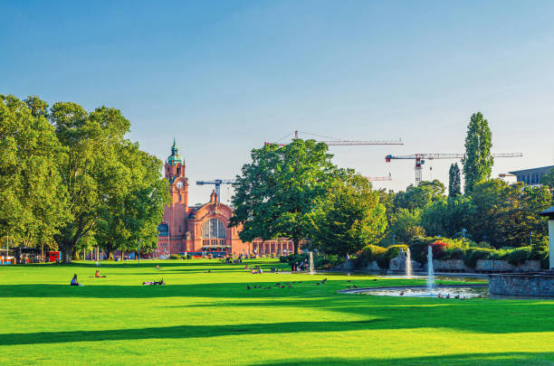 Wiesbaden, Germany, August 24, 2019: Hauptbahnhof central railway station Neo-baroque style building and Reisinger-Anlagen park with green trees and lawn in historical city centre, State of Hesse