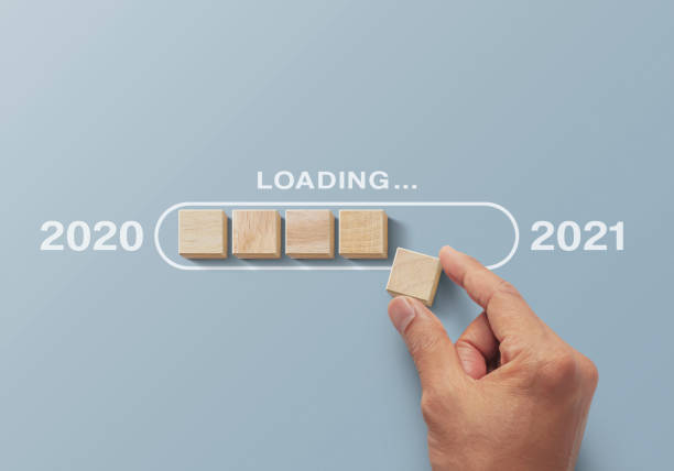 istock 2021 uploading, reboot, refresh or mindset concept. Hand putting wooden blocks in progress bar on gray background with the word 2021 uploading. 1294246890