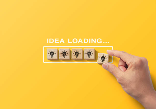 Idea uploading, reboot idea, refresh or creative mindset concept. Hand putting wooden blocks in progress bar on yellow background with the word idea uploading and light bulb icon. stock photo