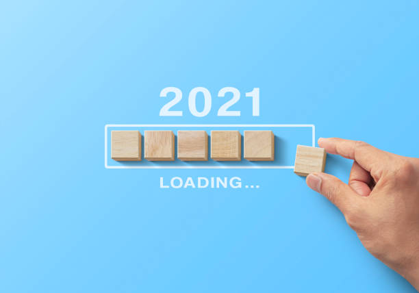 istock 2021 uploading, reboot, refresh or mindset concept. Hand putting wooden blocks in progress bar on blue background with the word 2021 uploading. 1294246893