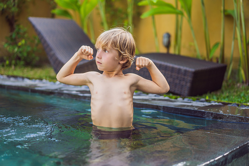 A boy shows his muscles after swimming.