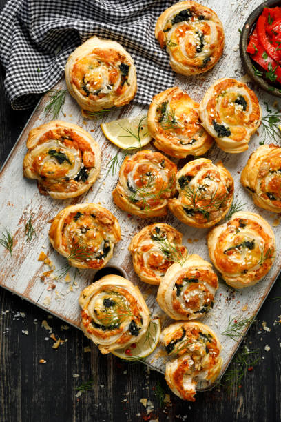 istock Puff Pastry Pinwheels stuffed with salmon, cheese and spinach served on a board on a black wooden table 1294253680