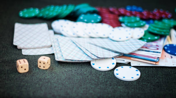 istock Casino poker chips stack with playing cards, dice and money on green felt background 1294257686
