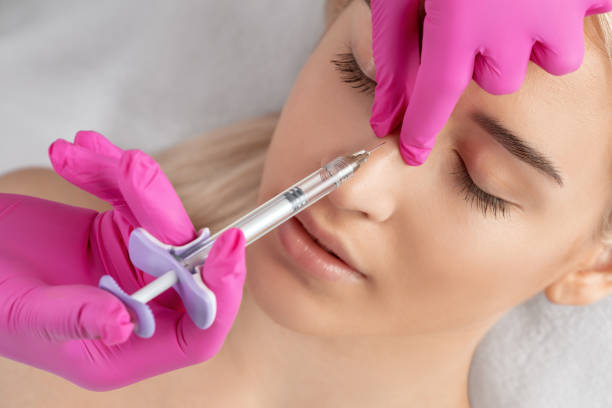 the doctor does injections to correct the hump on the nose with the beauty of the blonde. the beautician doees injections against wrinkles on the face. women's cosmetology in a beauty salon. - nose job imagens e fotografias de stock