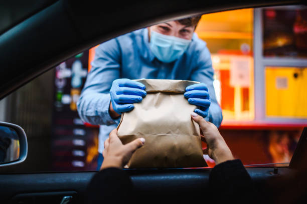 mujer recogiendo comida de restaurante de su auto en una foto de stock pick up curve.  servicio de recogida de alimentos y bebidas durante la pandemia covid. - drive in restaurant fotografías e imágenes de stock