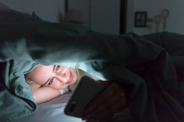 istock woman lying in bed under the blanket using smartphone at night.Insomnia, melatonin, internet addiction 1294260132