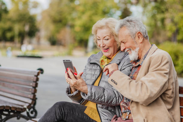 istock Senior couple is using mobile phone in park 1294261135