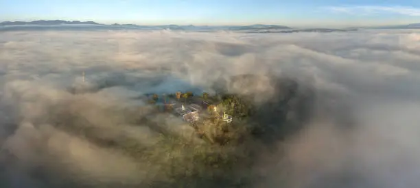 Photo of Aerial view in the morning with sea of fog at The iconic standing Buddha on Wat Phra That Khao Noi one of the most tourist attraction places in Nan province of northern Thailand during the sunrise