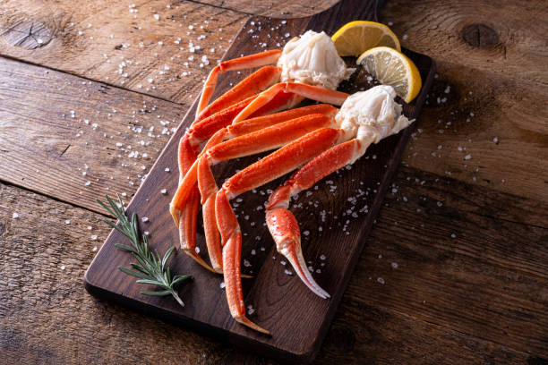 Snow Crab Leg Clusters Delicious snow crab leg clusters on a rustic wood table top. bunch stock pictures, royalty-free photos & images