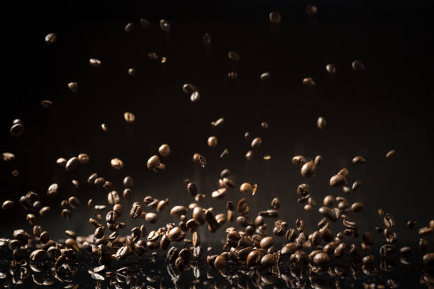 istock Flying weightless brown roasted coffee beans on a reflective surface and black background 1294266939