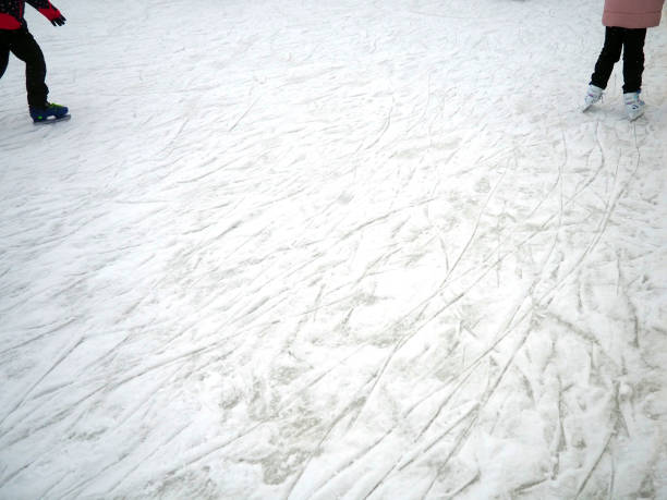 couverture de glace sur la patinoire avec de la neige et des traces de points de patin. jambes des personnes dans des patins. espace de copie. - ice hockey action ice skating ice skate photos et images de collection