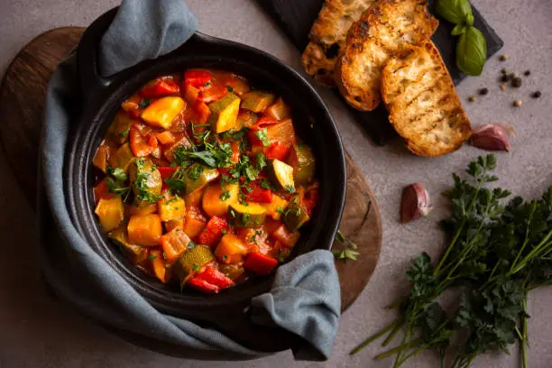 Photo of Cooked various chopped vegetables with herbs in a black cooking pot