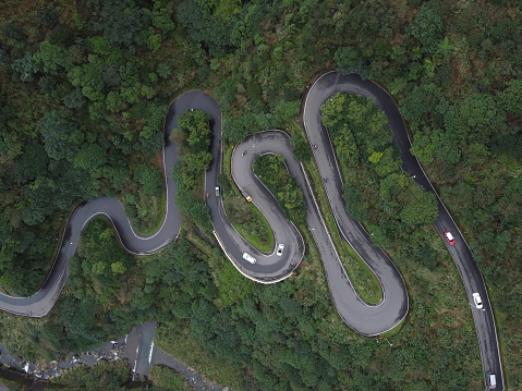 Cars driving along scenic mountain road with sharp hairpin turns near Jinguashi Waterfall.