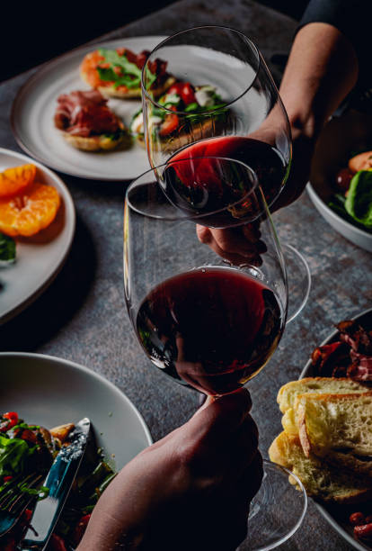 zwei gläser rotwein in frauenhänden im café - restaurant wine food dinner stock-fotos und bilder