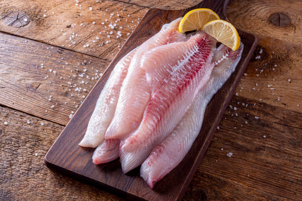 Fresh Haddock Fillets Fresh haddock fillets on a rustic table top with lemon wedges. haddock stock pictures, royalty-free photos & images