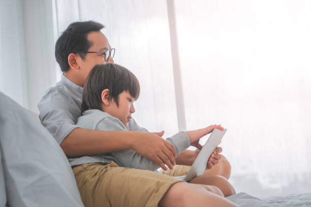 istock Father and son is using laptop computer on the bed together for Technology Educational concept. 1294286927