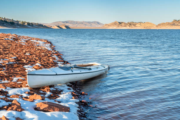 山の湖の岩場の海岸にデッキ探検カヌー - fort collins rock cliff mountain range ストックフォトと画像