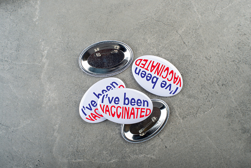 Vaccination campaign button pins on stone tabletop flat lay view