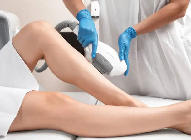 Elos epilation hair removal procedure on a woman"u2019s body. Beautician doing laser rejuvenation on the lower leg in a beauty salon. Removing unwanted body hair. Hardware ipl cosmetology