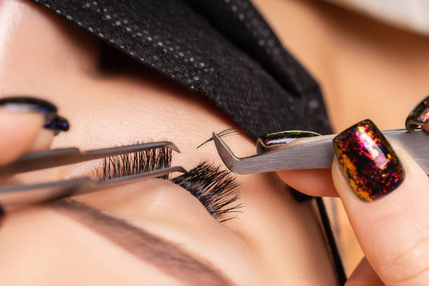 istock Eyelash Extension Procedure. Beautiful Woman with Extreme Long False Eyelashes. Makeup, Cosmetics. Beauty, Skincare. Woman in medical mask 1294303484