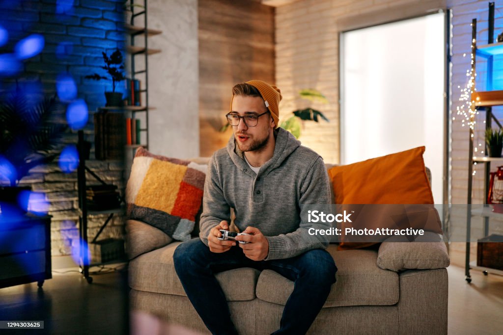 Online gaming concept. Guy playing football video game with joystick Video Game Stock Photo
