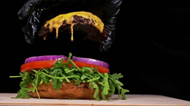 istock Craft burger is cooking on black background. Consist: sauce, arugula, tomato, onion, bacon, currant sauce, ricotta cheese, air bun and marble meat. 1294305020