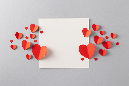 Red paper hearts with blank white note for Valentine’s Day message.