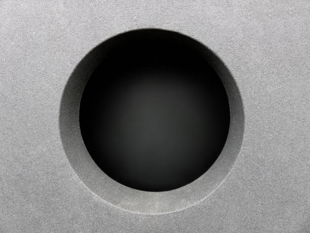 On the image we see a part of an abstract detail of modern architecture. A perfect round hole in a cementwall.