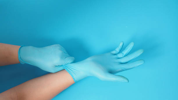 istock Hand is pulling medical gloves or surgical gloves on blue or Turquoise background. 1294308468