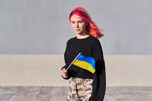 Estudiante adolescente con bandera de Ucrania, fondo gris de la pared al aire libre photo