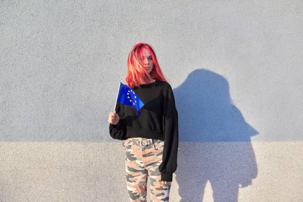 studentin teenager mit eu-flagge in der hand, graue außenwand hintergrund - adolescence flag university people stock-fotos und bilder