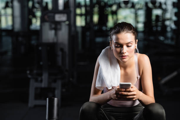 istock sportswoman messaging on cellphone while sitting in gym with towel on shoulder 1294310876