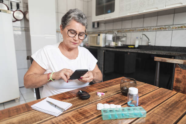 senior woman recording her blood sugar level with a smartphone - diabetes blood sugar test insulin glucose imagens e fotografias de stock
