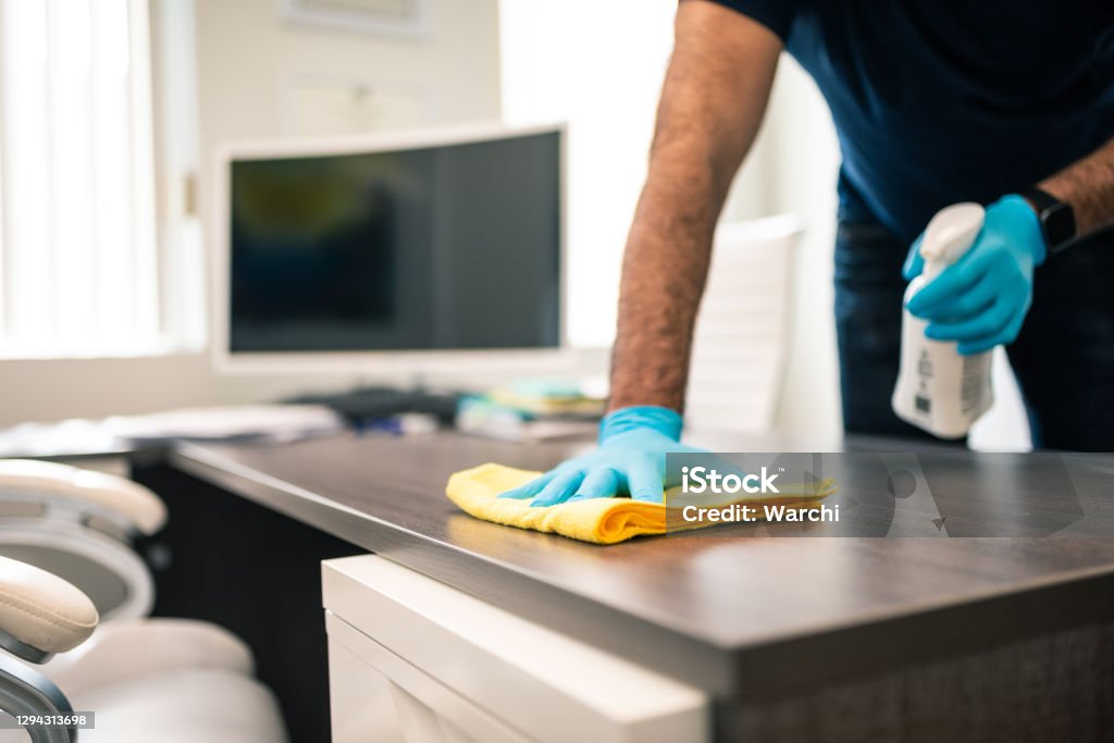 Man disinfecting an office desk Cleaning Stock Photo