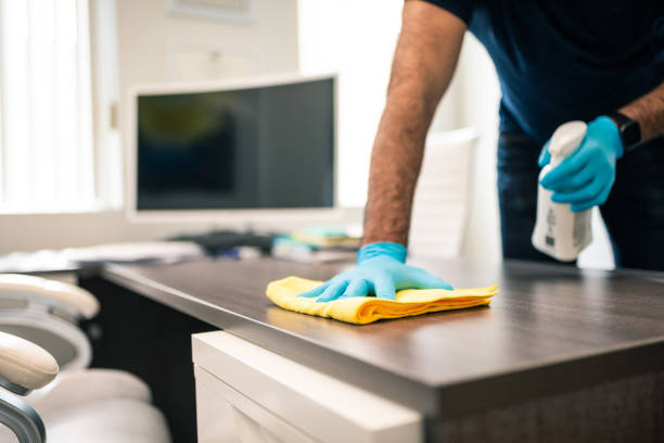 man disinfecting an office desk - limpando imagens e fotografias de stock