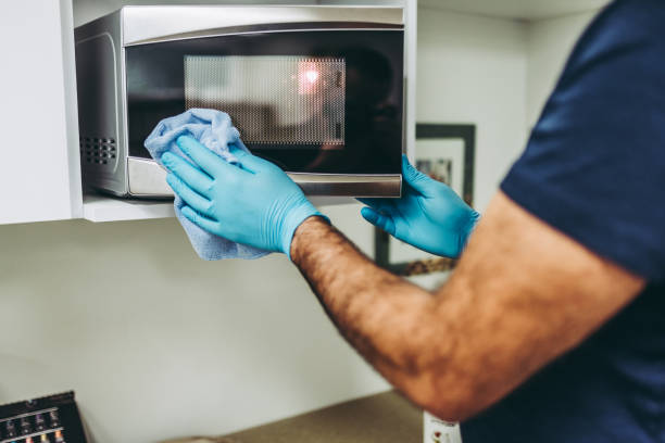 istock Hands of a janitor cleaning the microwave 1294314456