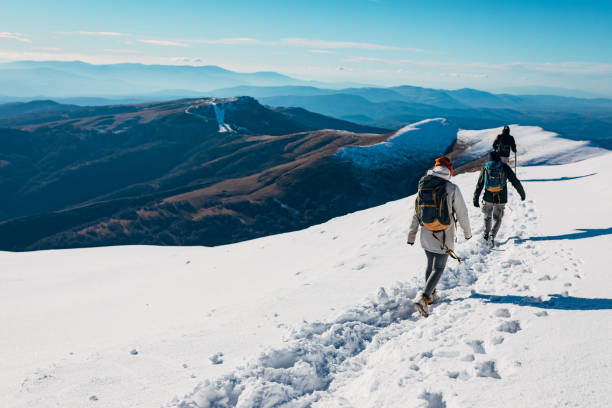 avventuroso gruppo di escursionisti che conquistano l'alta montagna innevata durante la giornata ventosa - snow hiking foto e immagini stock