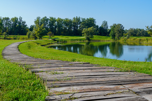 A beautiful view along wooden boardwalk along the shores of a calm lake \nD.H