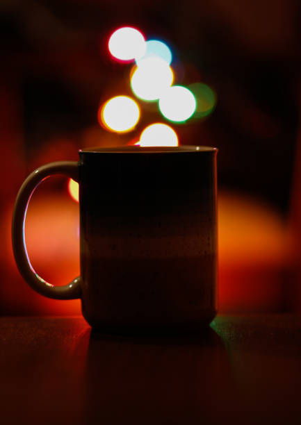 istock Colorful light bokeh and coffee mug on dark background 1294316811