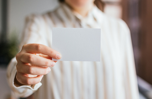 Blank business card mockup closeup held by a businesswoman. Logo and branding design template concept