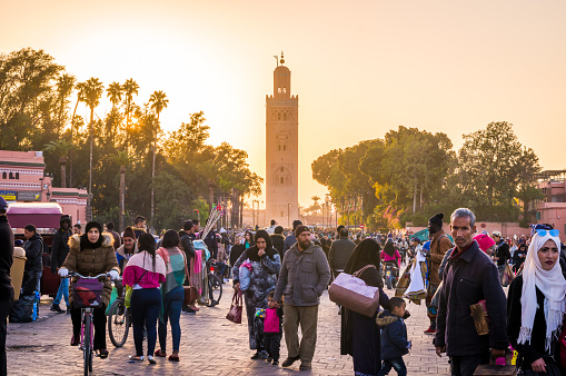 Marrakech, Morocco - January 19, 2018:tourists and locals in Djemaa el Fna Square with Koutoubia Mosque in the background at sunset