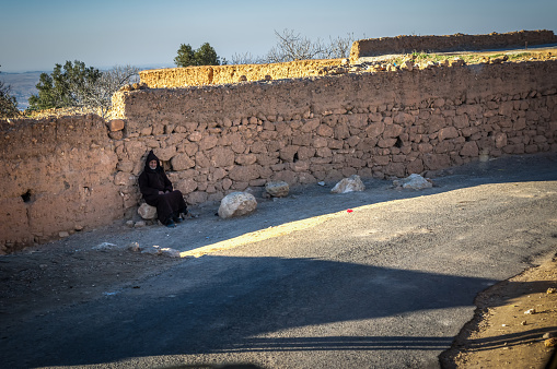 Aguegour, Morocco - January 20, 2018: Old berber man seated in a rock in Aguegour village, Al Haouz province, Morocco