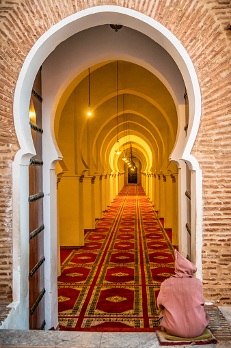 Marrakech, Morocco - January 20, 2018: man seated at the entrance of Koutoubia mosque in Marrakesh, Morocco