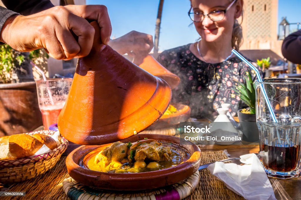 traditional Moroccan tajine with chicken, lemon and olives hand opening a traditional Moroccan tajine with chicken, lemon and olives in the restaurant in Marrakesh Morocco Stock Photo